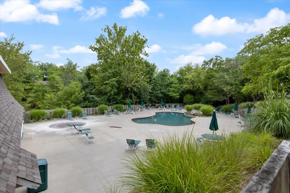 An inviting outdoor swimming pool area featuring lounge chairs, a hot tub, and surrounding greenery. The poolside setup is ideal for group activities like swimming, sunbathing, and socializing under the open sky, reflecting a vacation atmosphere.