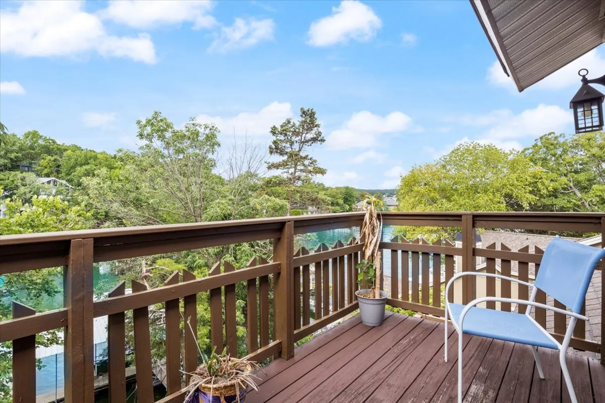 A serene exterior view from a wooden deck with a blue chair, potted plant, and a tranquil outlook over trees and the water. The scene evokes relaxation, stargazing, or enjoying a nightcap while taking in the lake views, aligning with the post-dining experience described in the section.
